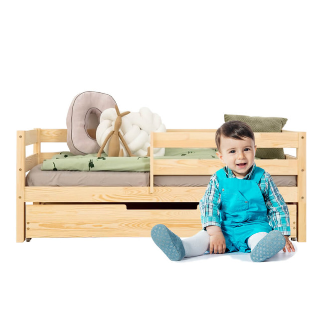 Un lit de transition pour jeune enfant avec barrière et tiroir, conçu spécialement pour accueillir un matelas bébé de 70x140, fabriqué en bois de pin par Adeko, sous le modèle CPD.