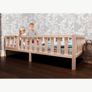 Alt text: "Lit à hauteur réduite Nido 80x160 avec barrière et porte blanche en bois massif, fabriqué artisanalement en Lettonie, idéal pour les enfants de 3 à 6 ans.