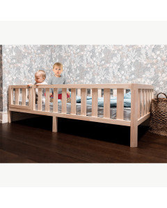 Alt text: "Lit à hauteur réduite Nido 80x160 avec barrière et porte blanche en bois massif, fabriqué artisanalement en Lettonie, idéal pour les enfants de 3 à 6 ans.