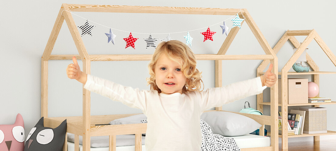 Photo d’un enfant présentant sa joie d’avoir un lit cabane en bois comme couchage