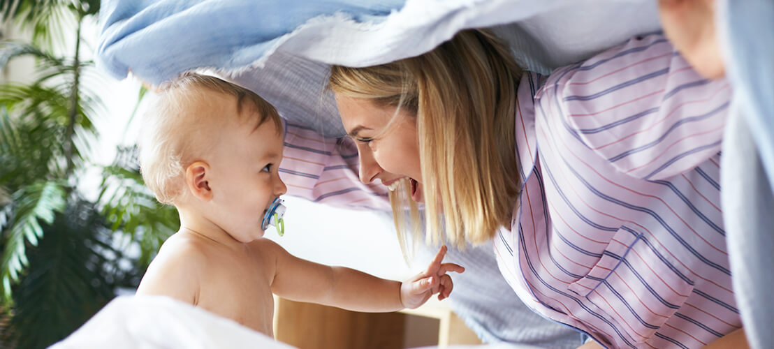 Maman et bébé jouant à cache cache dans le lit