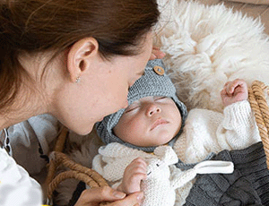 Maman embrassant son bébé endormi dans un couffin